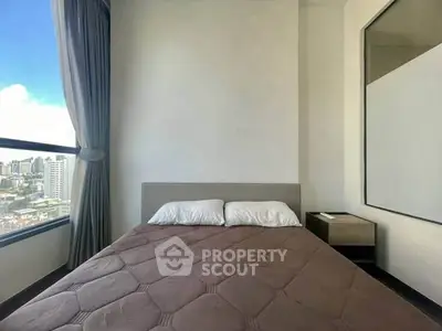 Modern bedroom with city view, featuring a cozy bed and large window for natural light.