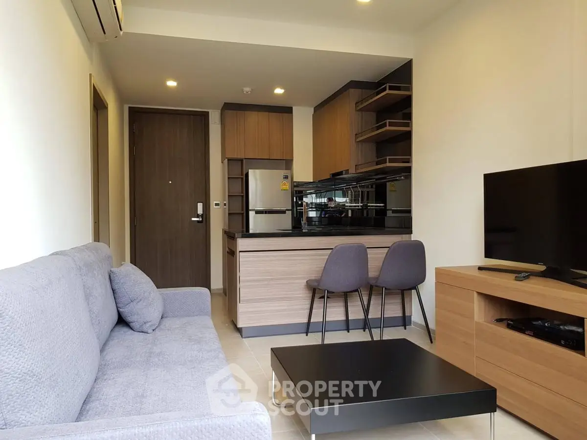 Modern living room with open kitchen, featuring sleek furniture and contemporary design.