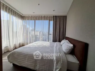 Spacious bedroom with large windows offering stunning city views, perfect for urban living.