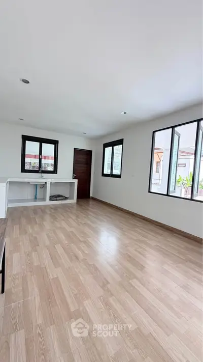 Spacious and bright living room with wooden flooring and large windows