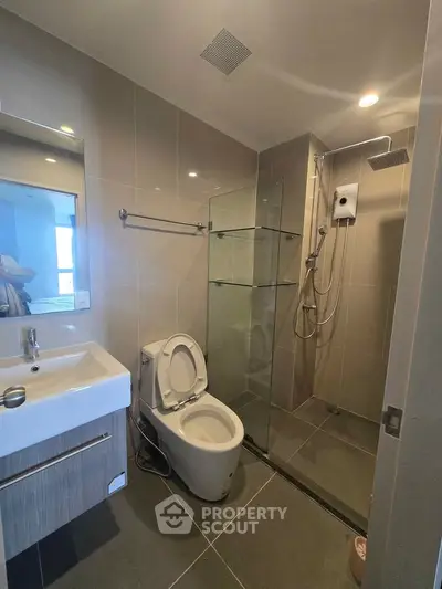 Modern bathroom with sleek fixtures and glass shower enclosure in a contemporary apartment.
