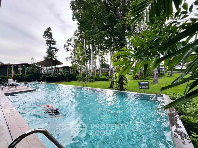 Luxurious outdoor pool surrounded by lush greenery in a serene setting.
