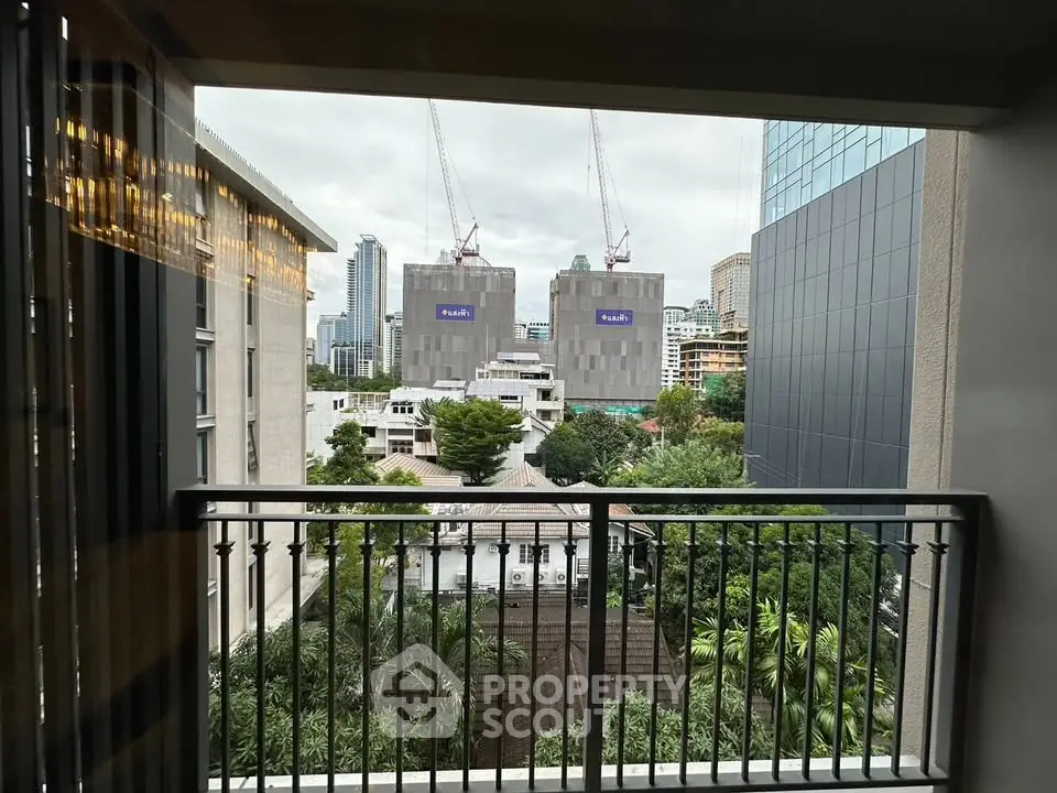 Stunning urban view from a modern balcony overlooking cityscape and construction cranes.