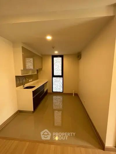 Modern kitchen with sleek cabinetry and glossy floor tiles in a compact space.