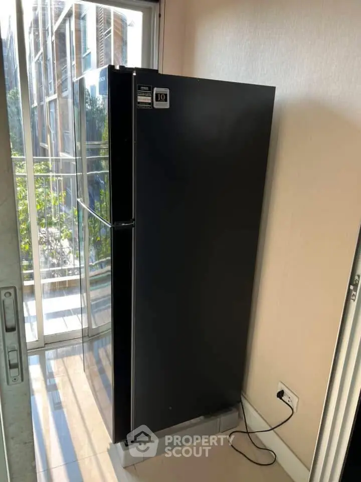 Modern kitchen with sleek black refrigerator and glass balcony doors.