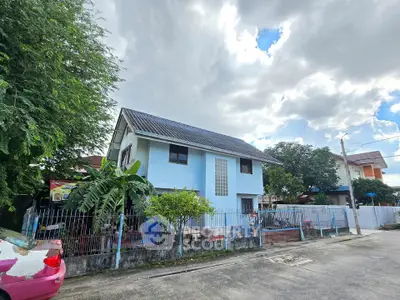 Charming two-story blue house with a fenced yard and lush greenery in a serene neighborhood.