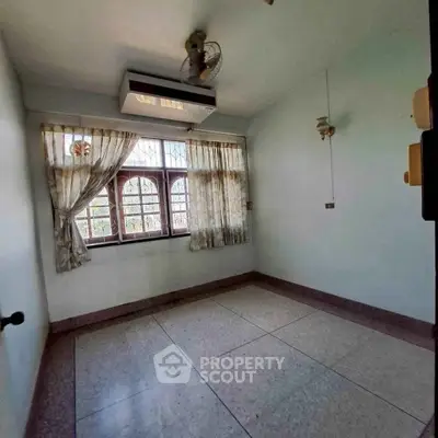 Spacious empty room with large window and ceiling fan, perfect for customization.