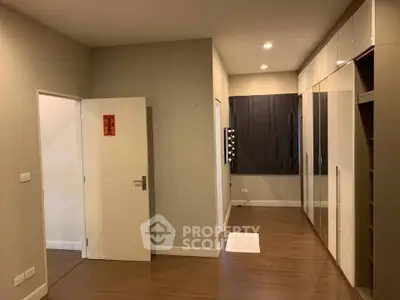 Spacious bedroom with modern closet and wooden flooring in a stylish apartment.