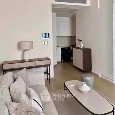 Modern living room with neutral tones, sleek furniture, and a compact kitchen area featuring a washing machine.