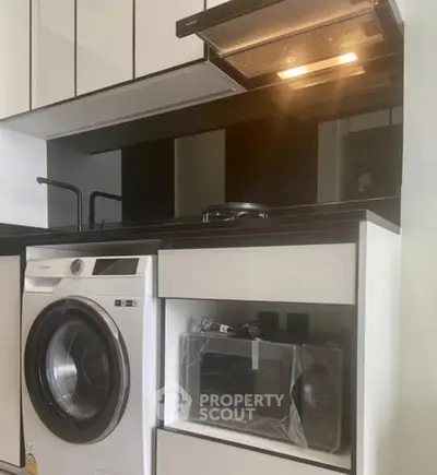 Modern kitchen with sleek appliances including washing machine and microwave