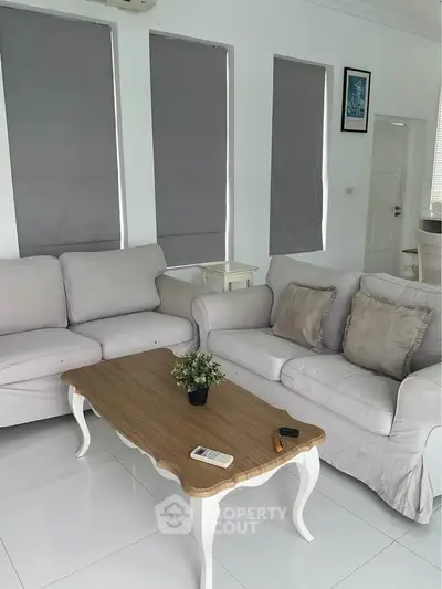 Charming living room with elegant white sofas and a stylish wooden coffee table, perfect for relaxation and entertaining.
