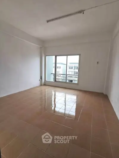 Spacious empty room with large window and tiled floor, perfect for customization.