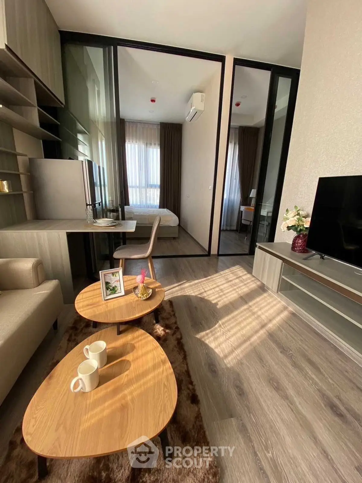 Modern living room with stylish furniture and natural light, featuring a cozy bedroom view.