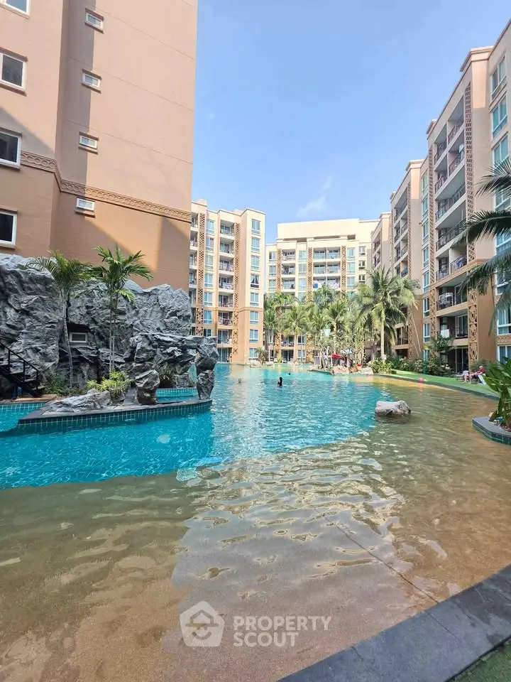 Luxurious apartment complex with stunning pool and tropical landscaping.