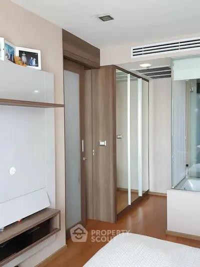 Modern bedroom with wooden flooring and mirrored closet doors