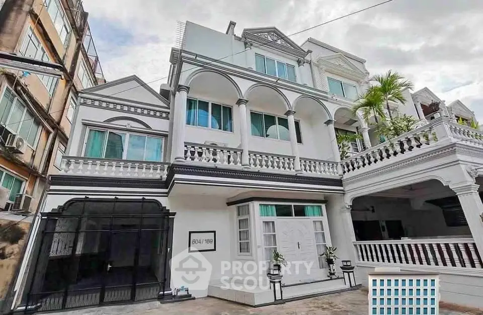 Elegant multi-story white building with classic architectural details and spacious balcony.