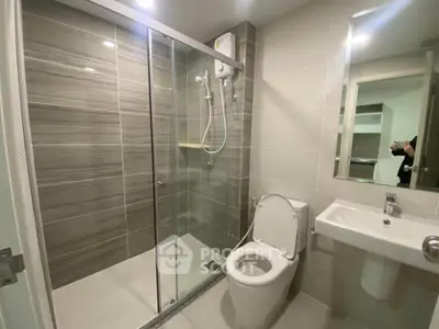 Modern bathroom with glass shower enclosure and sleek fixtures in a contemporary apartment.
