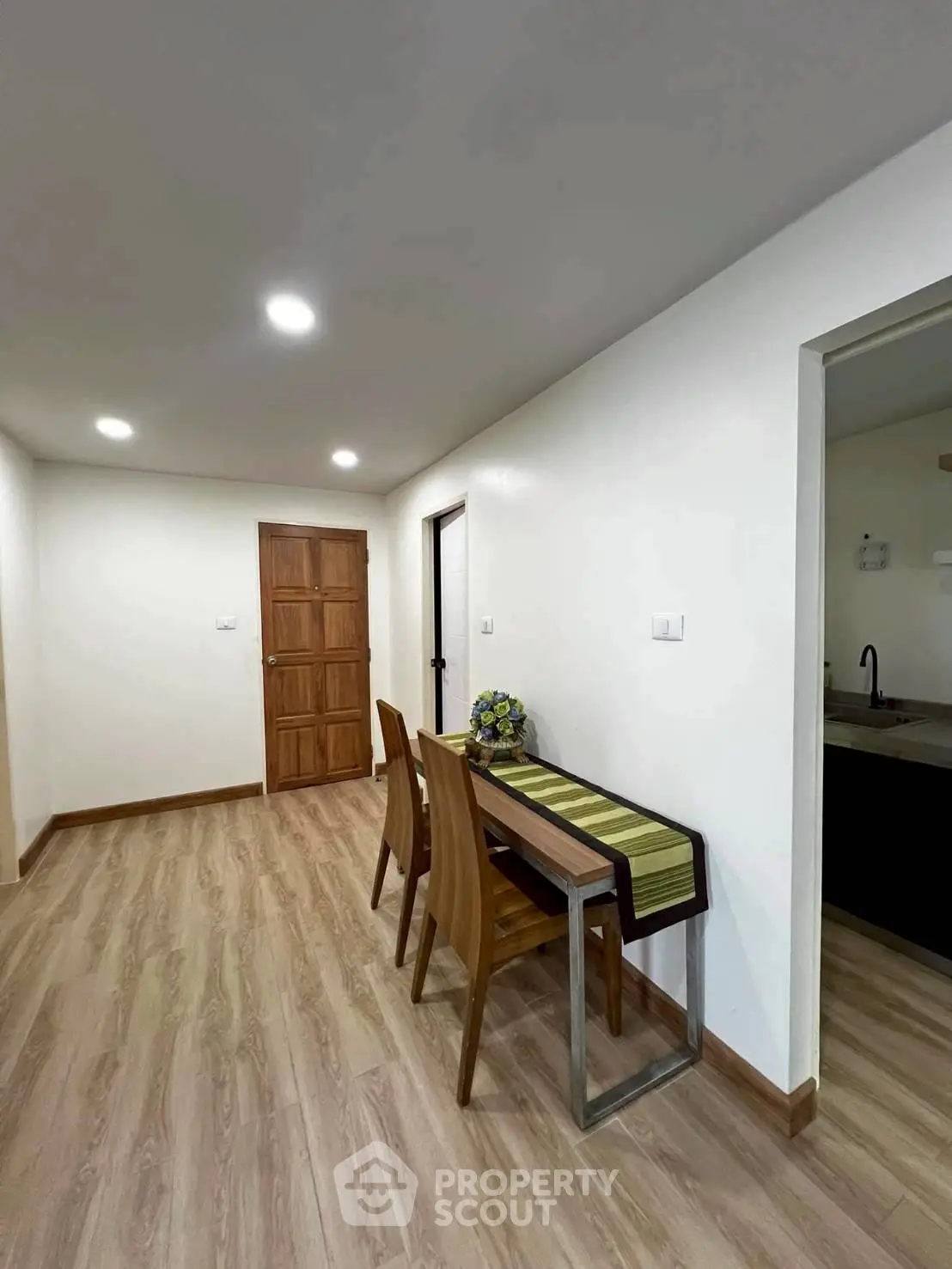 Modern dining area with wooden flooring and sleek furniture in a cozy apartment.