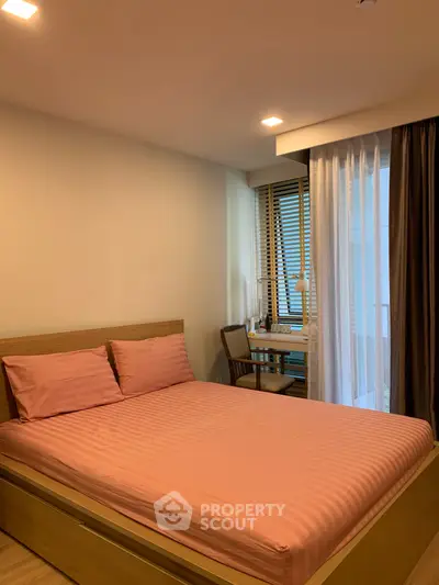 Cozy bedroom with pink bedding and a study desk near the window, perfect for relaxation and work.