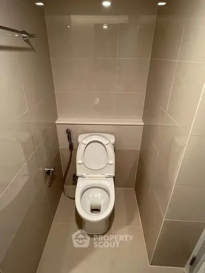 Modern bathroom with sleek tile design and toilet in compact space.