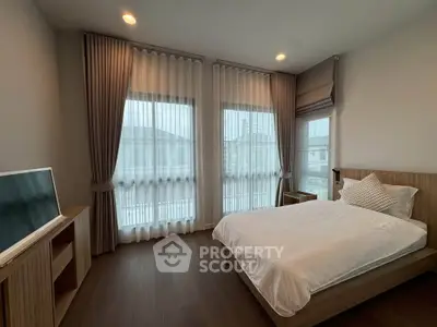 Spacious bedroom with modern decor and large windows offering natural light.