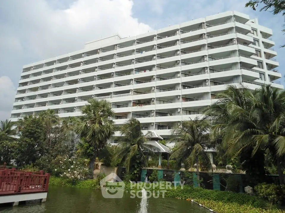 Stunning multi-story residential building with lush greenery and serene water feature.