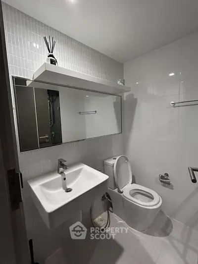 Modern bathroom with sleek fixtures and white tiles, featuring a wall-mounted sink and toilet.