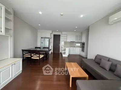 Spacious open-plan living room with modern kitchen and dining area, featuring sleek wooden flooring.