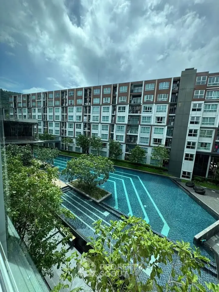 Modern apartment complex with stunning pool and lush greenery under a dramatic sky.