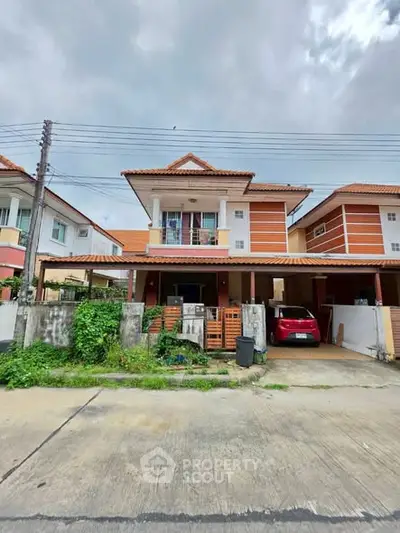 Charming two-story house with carport and lush greenery in a suburban neighborhood.