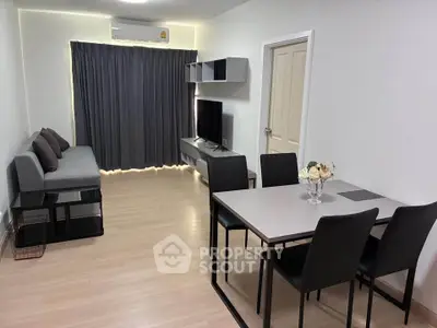 Modern living room with sleek furniture and dining area, featuring a cozy sofa and flat-screen TV.