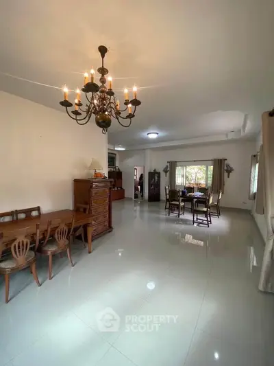 Spacious living room with elegant chandelier and dining area, perfect for family gatherings.