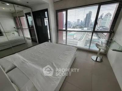 Modern bedroom with city view and large windows in high-rise apartment