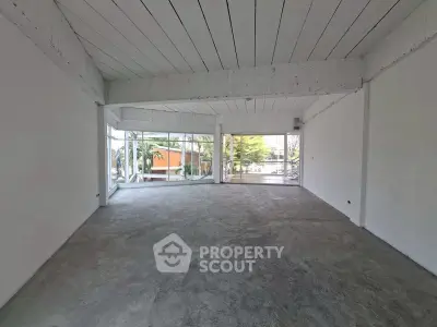 Spacious open-plan room with large windows and concrete flooring, ideal for customization.