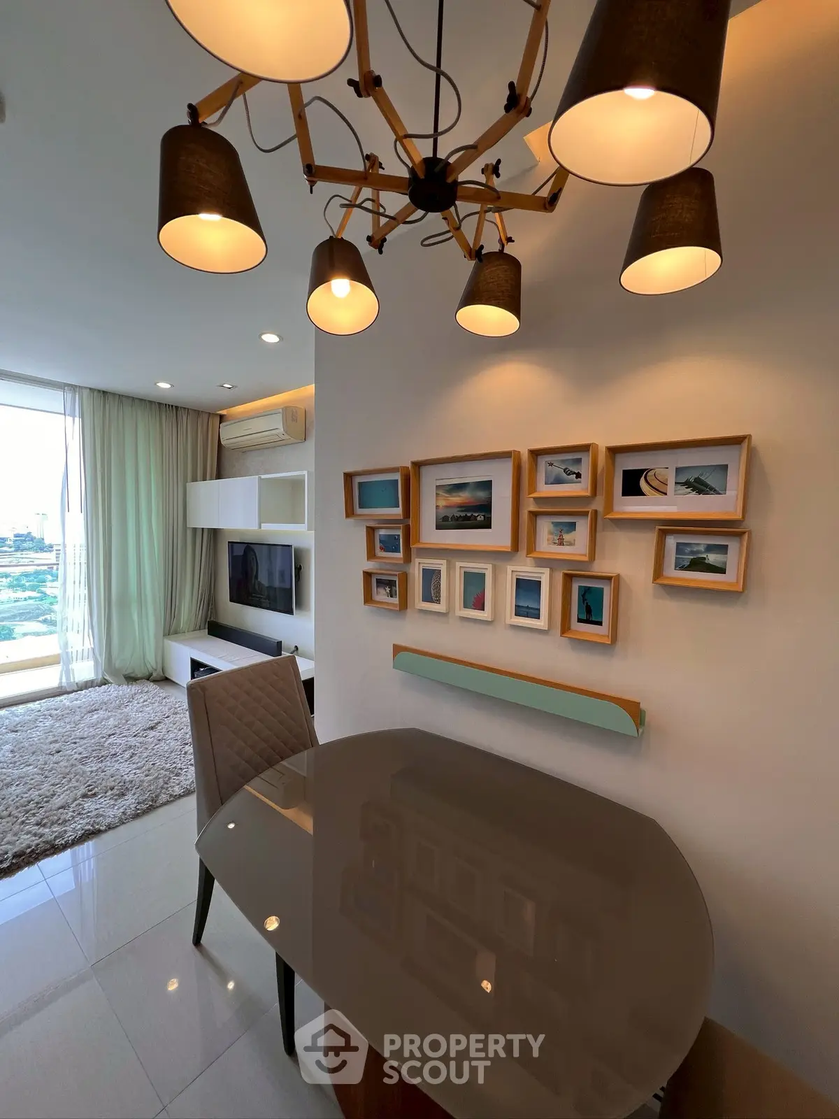 Stylish modern living room with elegant chandelier and wall art, featuring a cozy seating area and large window view.