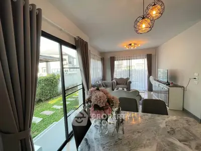 Modern living room with elegant decor and garden view, featuring stylish lighting and marble dining table.