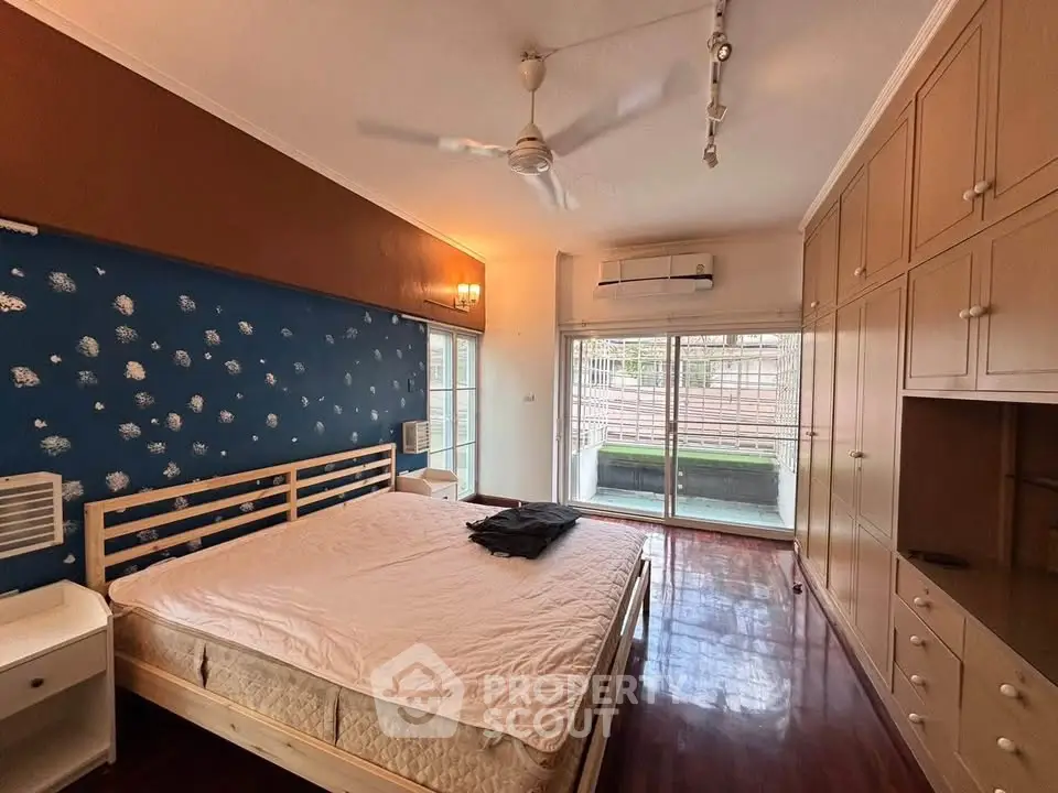 Spacious bedroom with large windows and built-in wardrobes, featuring elegant wooden flooring.