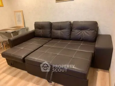 Modern living room with stylish brown leather sofa and wooden flooring