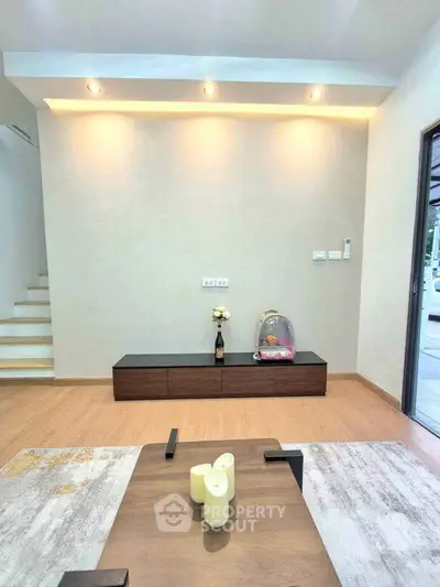 Modern living room with stylish decor and wooden flooring, featuring a sleek TV stand and ambient lighting.