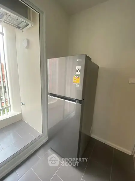 Modern kitchen with sleek stainless steel refrigerator and balcony view.