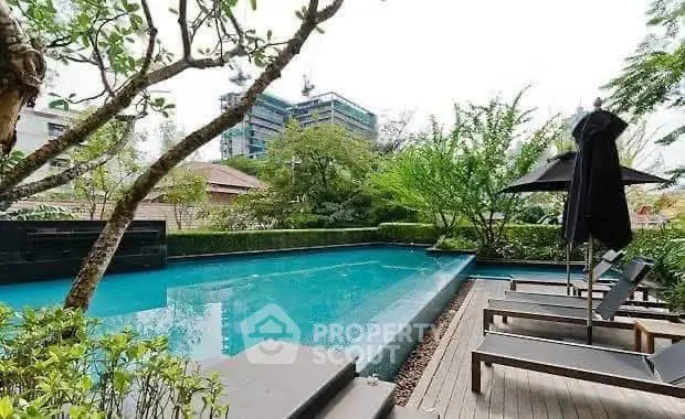 Luxurious outdoor pool area with sun loungers and lush greenery in a modern urban setting.