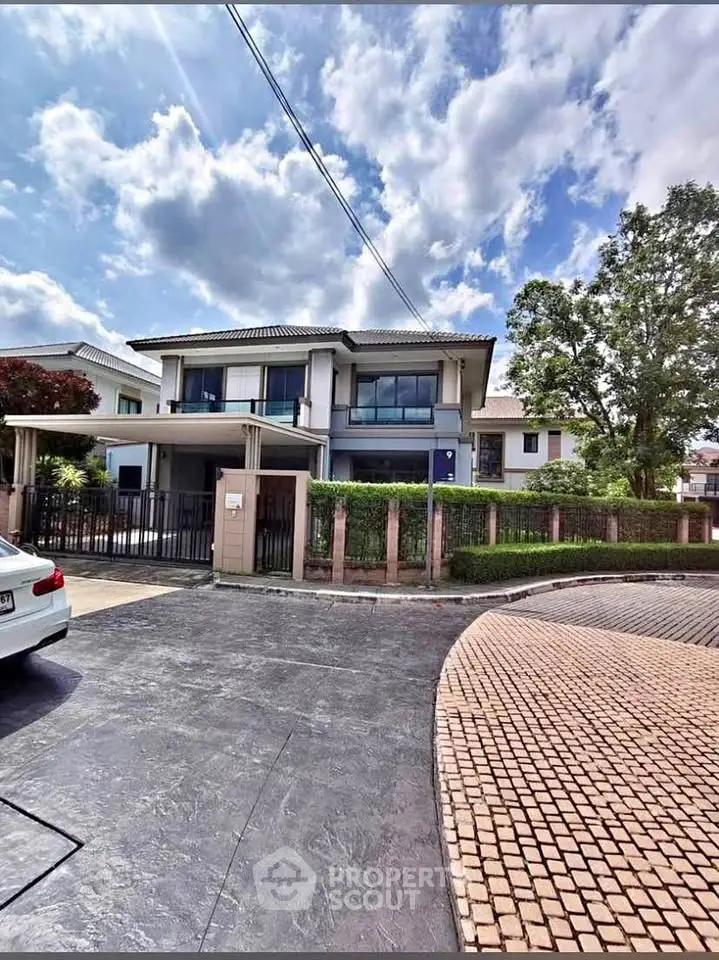 Stunning modern two-story house with spacious driveway and lush greenery under a bright blue sky.