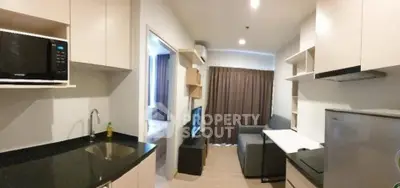 Modern compact kitchen with sleek appliances and cozy living area in a stylish apartment.