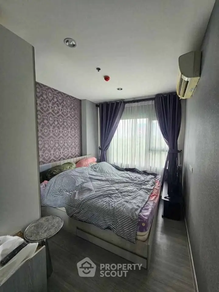 Cozy bedroom with modern decor and large window offering natural light.