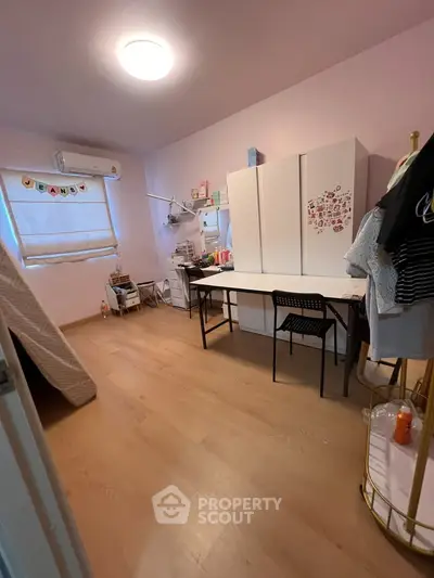 Cozy bedroom with wooden flooring, ample storage, and natural light.