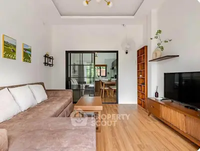 Modern living room with stylish furniture and open view to dining area, featuring wooden flooring and elegant decor.