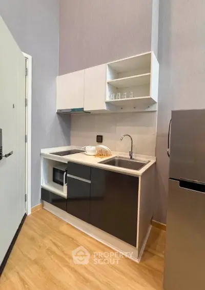 Modern compact kitchen with sleek cabinetry and stainless steel appliances in a stylish apartment.