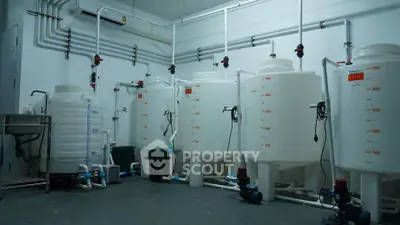 Industrial water storage tanks in a utility room with plumbing and equipment.