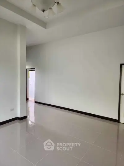 Spacious empty room with glossy tiled floor and white walls, ready for customization.