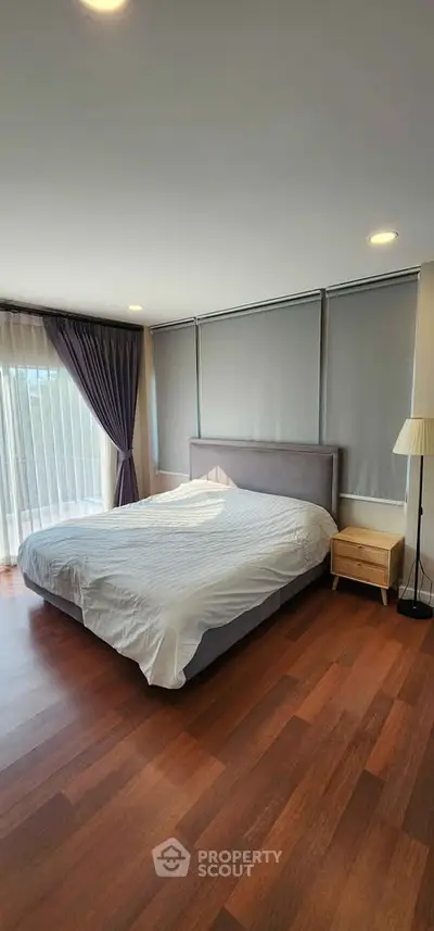 Spacious bedroom with large windows and elegant wooden flooring